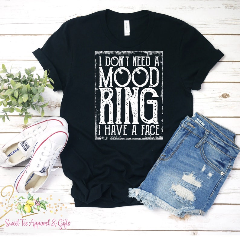 May include: Black t-shirt with white text that reads "I don't need a mood ring I have a face".