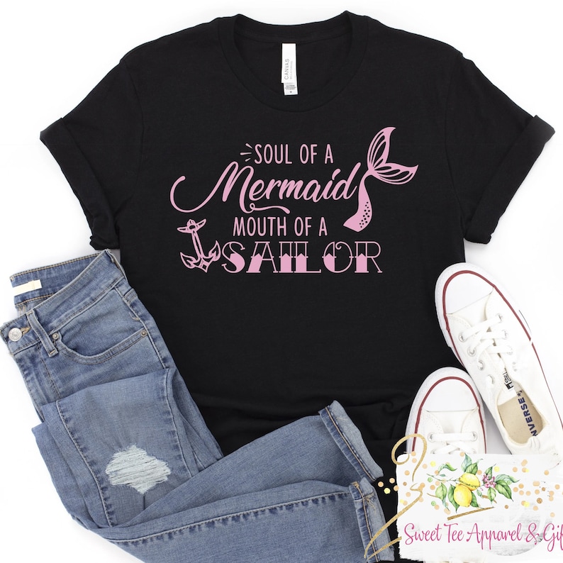 May include: Black t-shirt with a pink graphic that says "Soul of a Mermaid Mouth of a Sailor". The graphic includes a mermaid tail and an anchor.