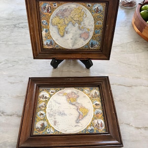 May include: Two framed vintage world maps. The maps are circular, with a detailed depiction of the continents in shades of yellow, pink, and green. The frames are dark brown wood, and the maps are surrounded by decorative borders.