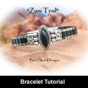 May include: A black and silver bracelet with a black gemstone in the center. The bracelet is on a brown rock with the text "Zuni Trail" and "Barb Smith Designs" above it. The text below the bracelet reads "Bracelet Tutorial".