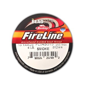 May include: A circular spool of The Beadsmith Berkley FireLine microfused braided bead thread in smoke color. The label displays 15 yards, 4 lb test, .005 inch diameter, and a barcode. The design features red, orange, and black graphic elements.