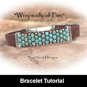 May include: A brown leather bracelet with turquoise beads and silver accents. The bracelet has a clasp closure and is labelled "Wrapsody of Fire" and "Barb Smith Designs".