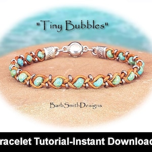 May include: A turquoise and brown leather bracelet with a silver magnetic clasp. The bracelet is woven with small turquoise beads and has the text "Tiny Bubbles" above it.