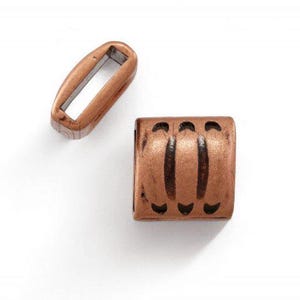May include: Two copper-colored metal jewelry components. One is a rectangular open-center link. The other is a cylindrical bead with three vertical, dark-colored decorative lines and small cut-out shapes.
