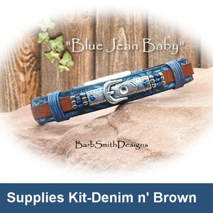 May include: A handcrafted bracelet with a denim and brown leather design. The bracelet features a silver-colored buckle and is accented with blue beads. The text "Blue Jean Baby" is visible above the bracelet.