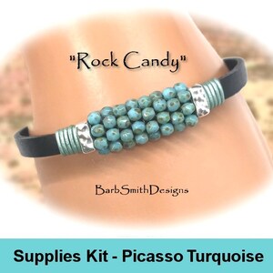 May include: A turquoise beaded bracelet with silver accents on a black leather band. The bracelet is labeled "Rock Candy" and "Supplies Kit - Picasso Turquoise".