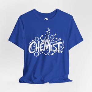May include: A royal blue short-sleeve t-shirt featuring a white graphic print on the chest. The design displays the word CHEMIST in bold lettering, surrounded by scientific illustrations including a flask, test tube, and molecules.