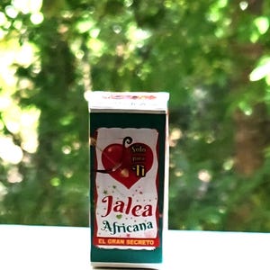 May include: A rectangular box with dark green sides and a white front panel. The front features a red heart graphic, the text Solo para Ti, Jalea Africana, and EL GRAN SECRETO in red and black lettering, with small decorative star accents.