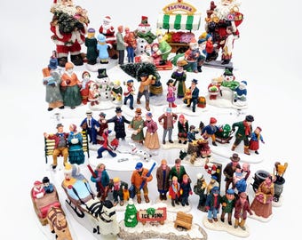May include: A collection of miniature Christmas-themed figurines featuring Santa Claus, snowmen, people in winter clothing, a flower cart, and an ice rink sign. The figures are painted in various colors and are sold individually as decorative items.