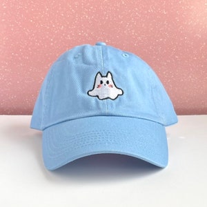 Könnte beinhalten: Eine hellblaue Baseballkappe mit einem weißen gestickten Geist mit einem niedlichen Gesicht.