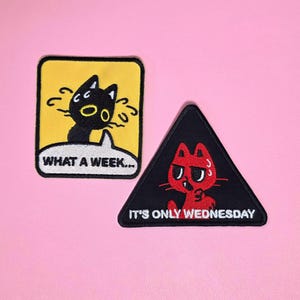 May include: Two embroidered patches. The rectangular yellow patch features a black cat with the text WHAT A WEEK... The triangular black patch features a red cat with the text IT'S ONLY WEDNESDAY. Both patches have black borders and white text.