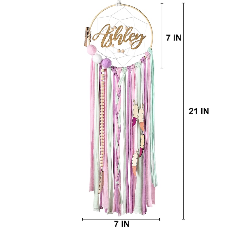 May include: A pink, green, and white dream catcher with the name "Ashley" written on it. The dream catcher is 7 inches in diameter and 21 inches long.