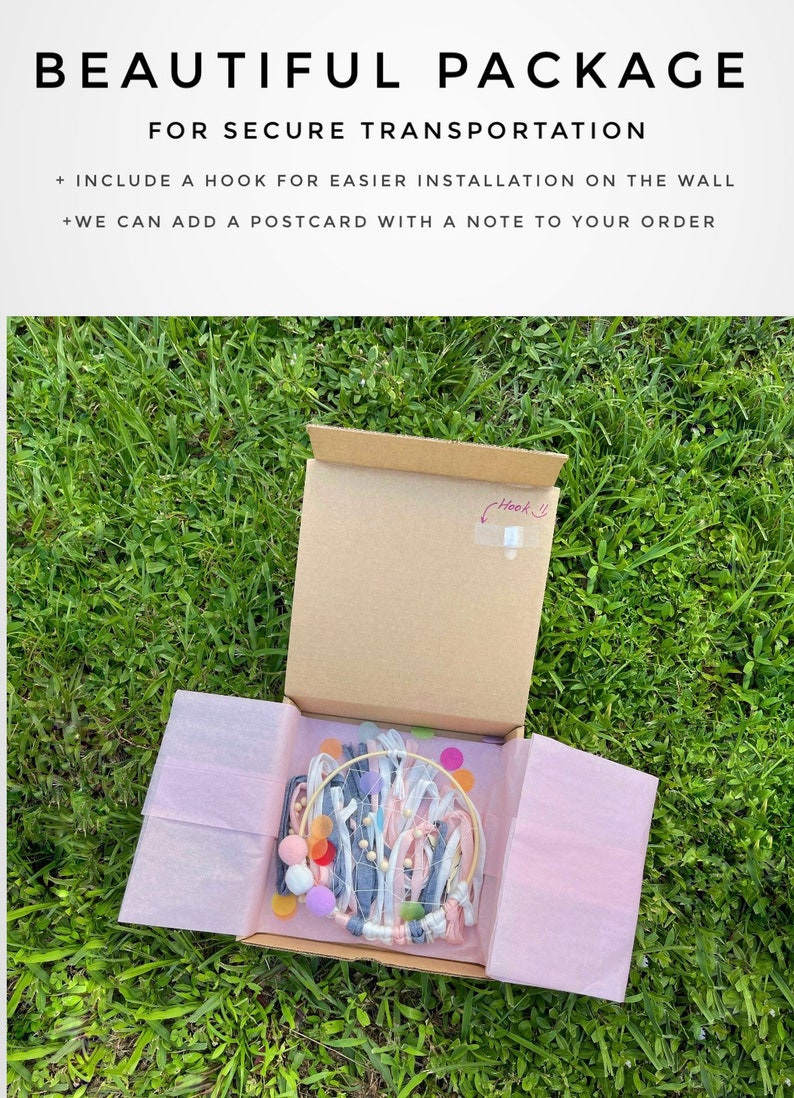 May include: A cardboard box with a pink tissue paper lining, containing a handmade dream catcher with white, pink, and blue ribbons, wooden beads, and colorful felt circles. The box is labeled with the text "Beautiful Package for Secure Transportation" and includes a hook for easy wall installation.