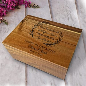 May include: A wooden box with a hinged lid, engraved with the words "Never Underestimate the Difference You've Made and the Lives You've Touched." The box also includes "HAPPY RETIREMENT" and the name "Olivia Clark" with the date "MAY 15, 2025."