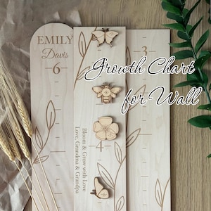May include: Wooden growth chart with engraved markings and decorative wooden cutouts of a butterfly, bee, and flower. The chart includes the text "Growth Chart for Wall" and the name "Emily Davis".