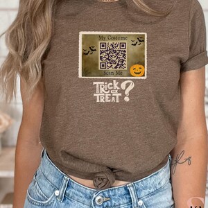 May include: A brown t-shirt with a vintage-style design featuring a QR code with the text "My Costume Scan Me" and the text "Trick or Treat?" below it.