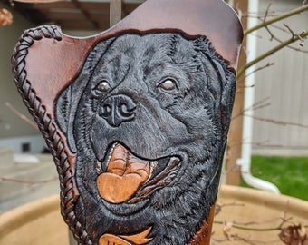 May include: A brown leather holster with a carved image of a black dog's head. The holster has a banner that reads "House of Falciani Est. 2022".
