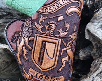 May include: A brown leather holster with a carved design featuring a coat of arms, a lion, a unicorn, and the text "OSSOLINSKI 1695".