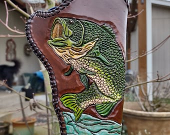 May include: A brown leather holster with a tooled design of a bass fish jumping out of the water. The holster is decorated with green, brown, and blue colours.