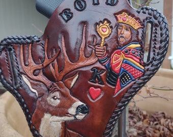 May include: A brown leather holster featuring a deer and a king playing card design. The word "BOYD" is embossed at the top. The holster has a braided edge and a black gun is partially visible.