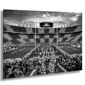 A black and white photograph of a football stadium during a game, with a large crowd of spectators filling the stands.