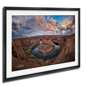 a stunning natural landscape with a winding river surrounded by towering red rock formations under a dramatic cloudy sky.