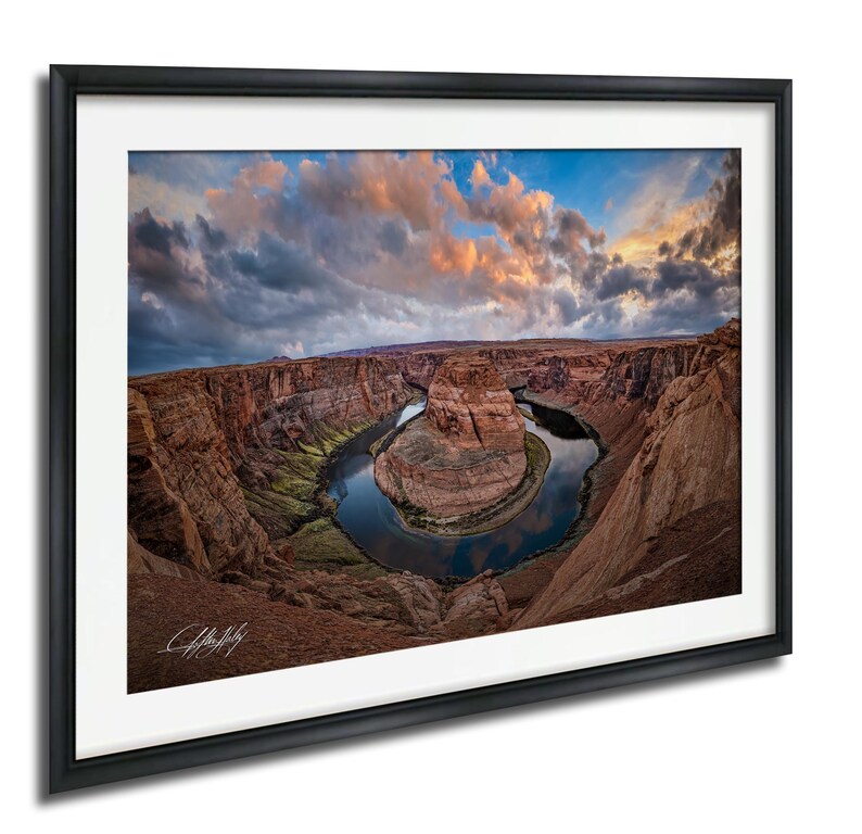 a stunning natural landscape with a winding river surrounded by towering red rock formations under a dramatic cloudy sky.