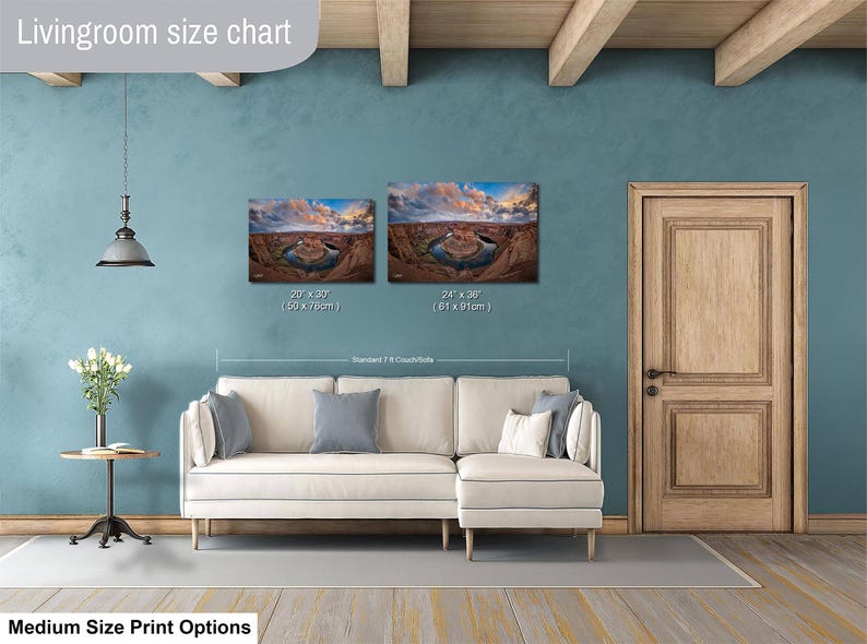 a living room with a white sofa, a wooden door, and a painting of a desert landscape on the wall. The living room appears to be well-lit and decorated with a potted plant and a vase.
