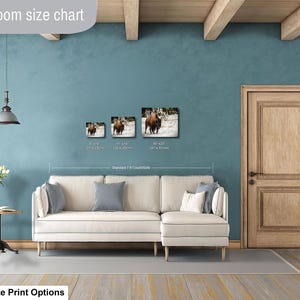 a living room with a white sofa, a wooden door, and a hanging light fixture. There are three framed pictures of animals on the wall, and the text indicates that the living room is designed for smaller size print options.