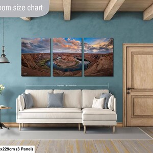 The image is a livingroom with a large living room size chart on the wall, featuring a three-panel landscape painting depicting a scenic desert landscape with a winding river.