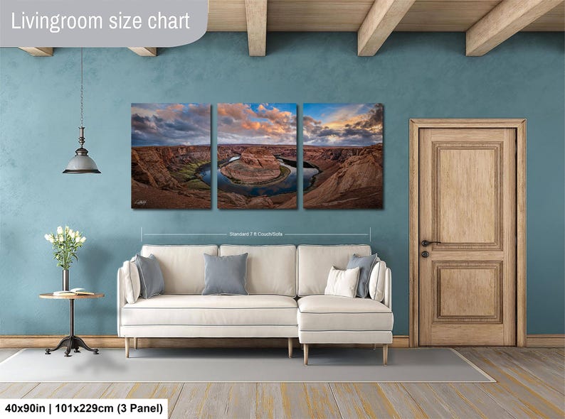 The image is a livingroom with a large living room size chart on the wall, featuring a three-panel landscape painting depicting a scenic desert landscape with a winding river.