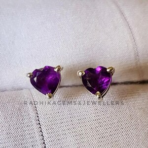Puede incluir: Un par de pendientes de botón de plata en forma de corazón con piedras preciosas de amatista púrpura.