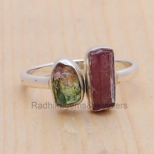 Könnte beinhalten: Ein Silberring mit zwei rohen, mehrfarbigen Turmalin-Edelsteinen. Der größere Stein ist rosa und der kleinere ist grün, rosa und gelb.