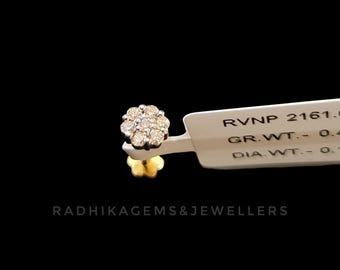 May include: A gold stud earring with a flower design, featuring multiple small diamonds. The earring is displayed against a black background with a white tag that has text. The text "RADHIKAGEMS&JEWELLERS" is also visible.