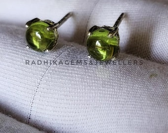 Könnte beinhalten: Ein Paar silberne Ohrstecker mit grünen Edelsteinen. Die Ohrringe sind in einem schlichten, klassischen Stil gehalten.