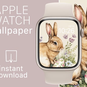 Puede incluir: Un Apple Watch con una correa beige claro muestra un fondo de pantalla con temática de Pascua. El fondo de pantalla presenta un conejo marrón, elementos florales y huevos de Pascua decorados. Las palabras "APPLE WATCH wallpaper" y "instant download" también son visibles.