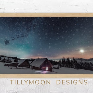 May include: A framed winter scene with a snowy mountain landscape and a small cabin with a lit window. The sky is filled with stars and snowflakes, and Santa's sleigh is flying overhead. The image is titled "TILLYMOON DESIGNS".