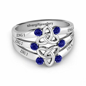 May include: A silver ring with a Celtic knot design and six blue gemstones. The ring has four bands with the words "ENG 1", "ENG 2", "ENG 3", and "ENG 6" engraved on them.