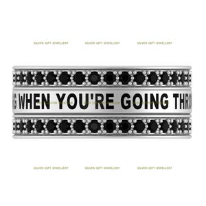 Op de afbeelding: Zilveren ring met zwarte stenen en de inscriptie "WHEN YOU'RE GOING THROUGH"