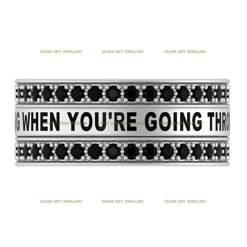 Op de afbeelding: Zilveren ring met zwarte stenen en de inscriptie "WHEN YOU'RE GOING THROUGH"