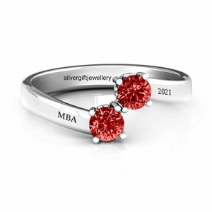 May include: A silver ring with two red gemstones and the inscription "MBA" and "2021" on the band.