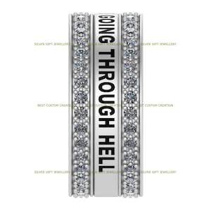 Op de afbeelding: Een zilveren ring met een band van kleine heldere stenen en de woorden "GOING THROUGH HELL" gegraveerd aan de zijkant.