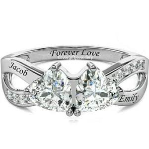 May include: A silver ring with two heart-shaped stones and the words "Forever Love" engraved on the band. The names "Jacob" and "Emily" are also engraved on the ring.