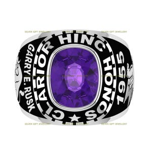 May include: A silver class ring with a black background and purple gemstone. The ring features the text "GARRY E. RUSK", "WARRIOR", "HIGH SCHOOL", "1955", and a star.