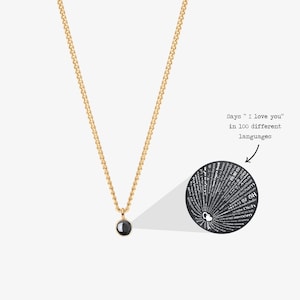 May include: A gold chain necklace with a black round pendant. The pendant has a hidden message that says "I love you" in 100 different languages.