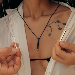 May include: Two silver and gold necklaces with bar pendants. The silver pendant says "strength & beauty" and the gold pendant says "eternal sunshine".