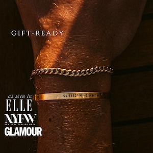 May include: Gold-toned stainless steel bracelets. One is a curb chain, the other a thin band with coordinates. The image includes the text "GIFT-READY" and "ELLE NYFW GLAMOUR". The bracelets are made of 316L stainless steel and 18K gold.