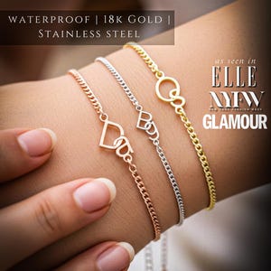 May include: Three fine bracelets in gold, silver, and rose gold are shown. Each bracelet has a unique charm: a heart, a stylized letter, and a circle. The image includes text that reads "WATERPROOF | 18K GOLD | STAINLESS STEEL" and "ELLE NYFW GLAMOUR."