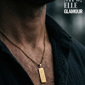 Può includere: Collana con pendente rettangolare dorato e catena. Il pendente presenta coordinate incise. L'immagine include anche il testo "AS SEEN IN NYFW, ELLE GLAMOUR" e "18K Gold Option".