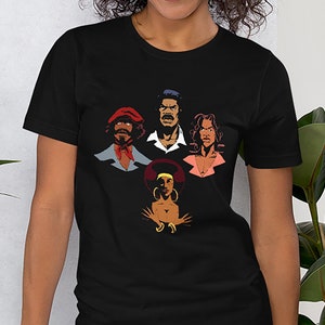 May include: A black t-shirt with a graphic of four cartoon faces. The faces are in a circle and are all different colors. The faces are of a man with a red hat, a man with a blue shirt, a woman with a pink shirt, and a woman with a yellow shirt.